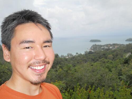 Verner Wilson III smiling outdoors with a coastal landscape in the background
